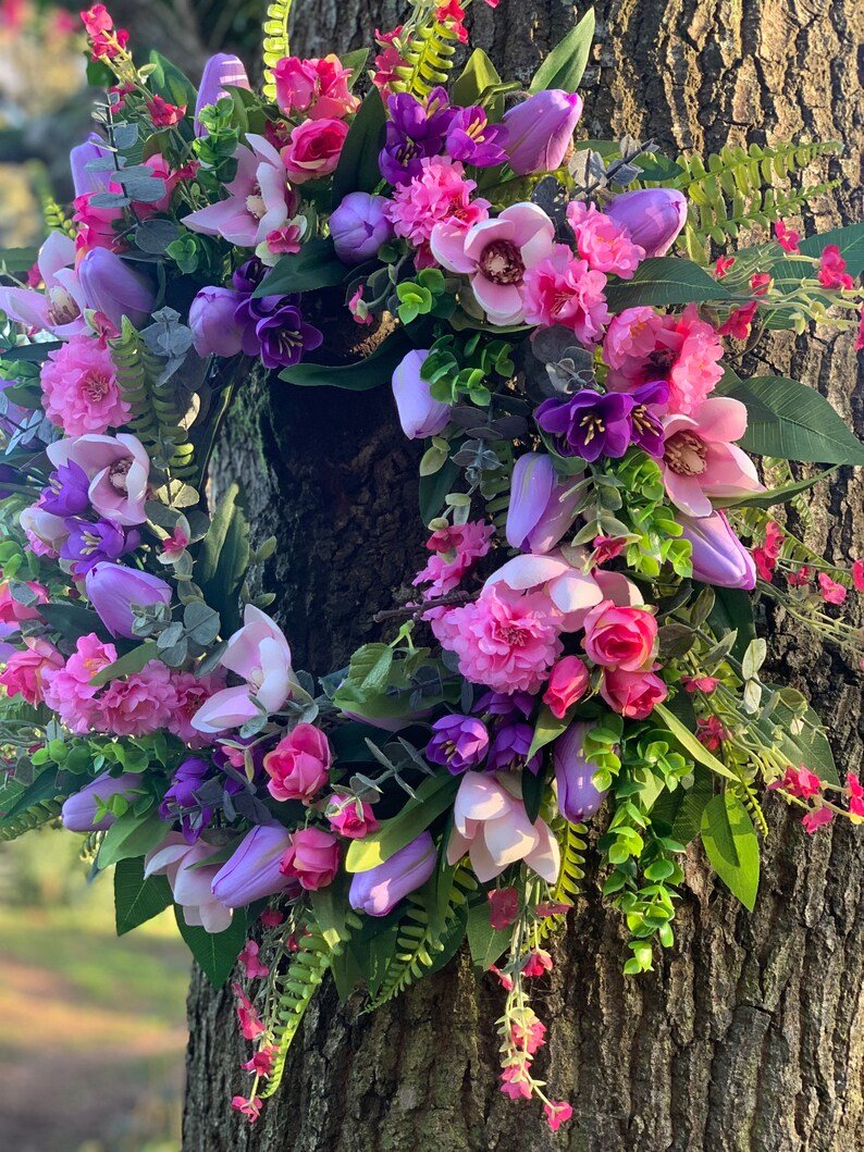 Handmade spring faux flower door wreath in pinks, purples and green.