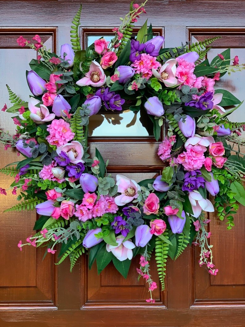 Handmade spring faux flower door wreath in pinks, purples and green.