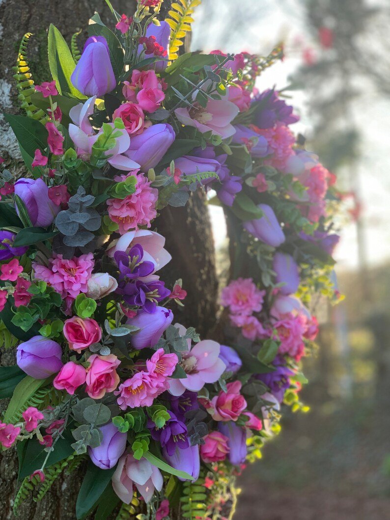 Handmade spring faux flower door wreath in pinks, purples and green.