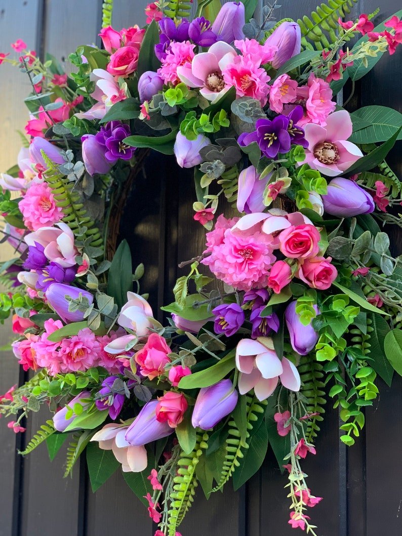 Handmade spring faux flower door wreath in pinks, purples and green.