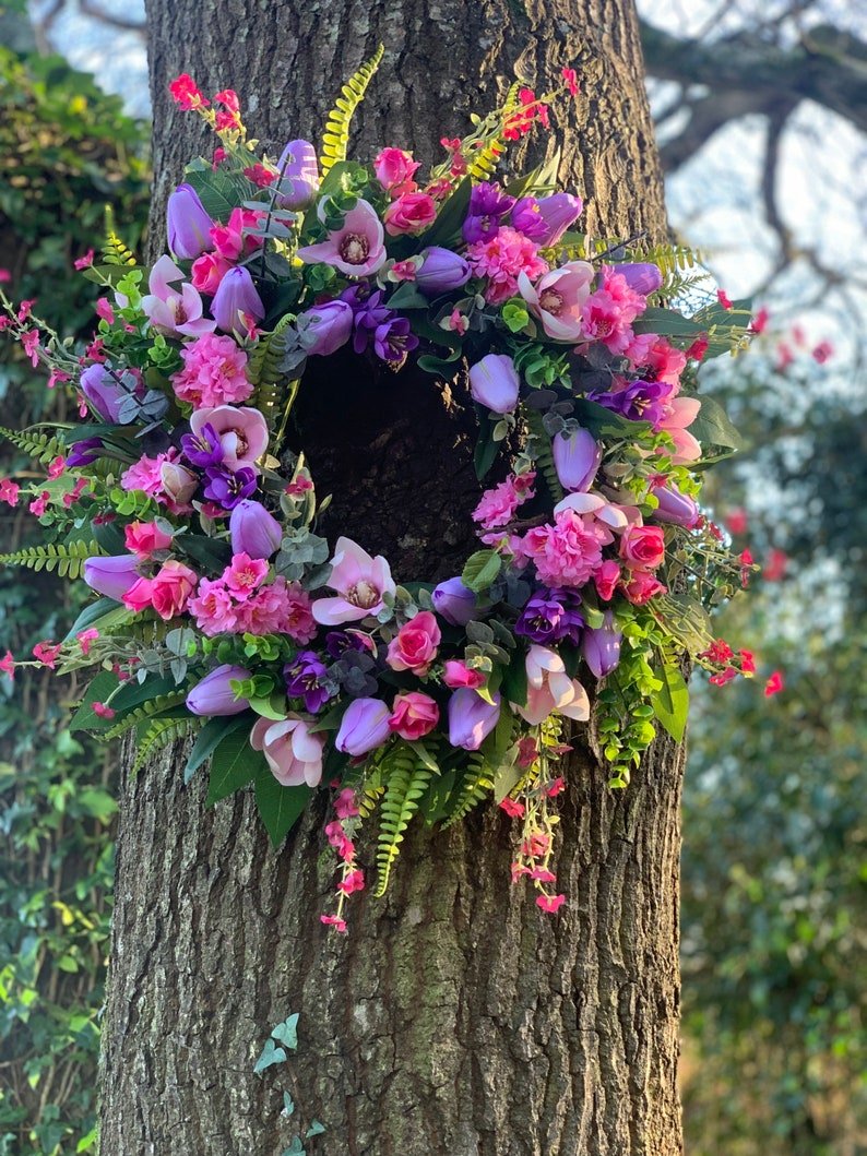 Handmade spring faux flower door wreath in pinks, purples and green.